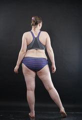 plus size woman shows her body in stretch marks and hair with cellulite and encourages you to love and accept yourself in any way . black background in the Studio. full- length photo.