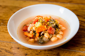 Close up of vegetable soup with kale, chickpeas, carrots, tomato, and lemon zest