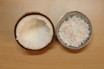 Fototapeta na wymiar Coconuts with coconut flakes and stainless steel Bowl are isolated on a wooden table, top view