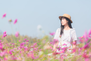 Panoramic view of young lady in white dress walking in the pink flower field meadow in the countryside with copy space for graphic design purpose
