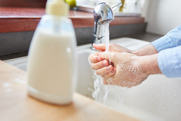 Seniorin beim Hände waschen mit Seife zu Hause