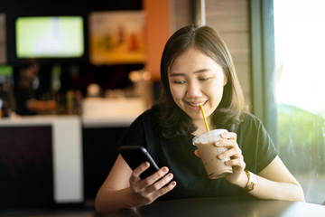 Beautiful happy Asian woman sitting at the coffee shop and restaurant, woman looking away with copyspace on blurred background. thoughtful and inspired creativity woman enjoy relaxing at coffee shop.