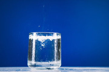 Glass of still water isolated on blue background