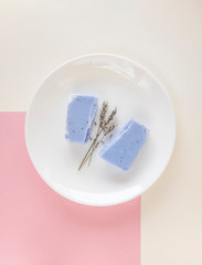 Homemade lavender soap bar and dry lavender flowers on minimalistic background. Set of plastic free and zero waste body care items.