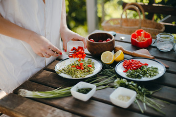 Woman's hands adding chopped pepper, cooking guacamole. Picnic summer cooking.