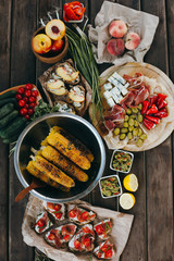 Summer picnic or BBQ food concept. Selection of vegetables, sandwiches, grilled corn and meat. Top view table scene on a wood background.