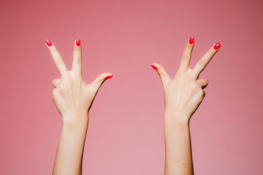 Woman's hands with bright manicure isolated on pink background three six