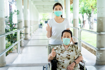 Young Asian grandchild taking care her grandmother sitting on wheelchair. Grandmother almost 90...
