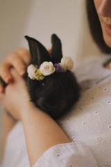  Easter bunny in a wreath of flowers on the hands of a girl