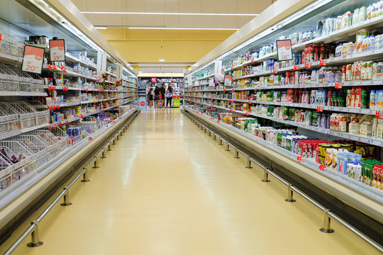 Belgorod, Russia - July 14, 2019: Long passage with food products for sale, exposed in refrigerators and shelves in Auchan supermarket. Dairy department.