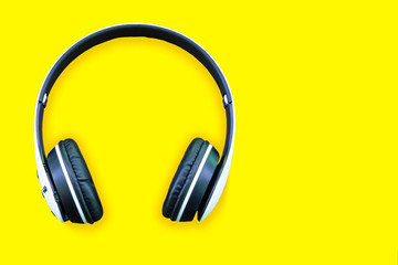 Minimalistic top view composition with white headphones on bright yellow background with a lot of...