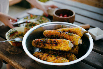 Grilled corn with spices in a metal bowl on a wooden table
