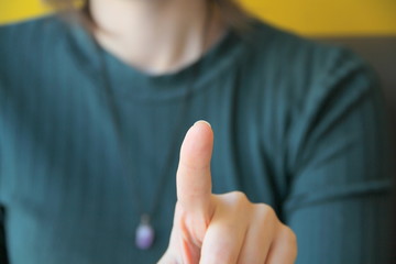 Girl holds index finger in front of her, points towards the viewer and camera