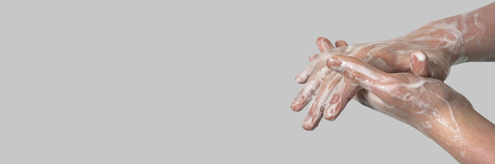 Fototapeta premium Hands of a young guy in soapy foam on a gray background. Hand washing. Minimal hygiene, virus protection concept.