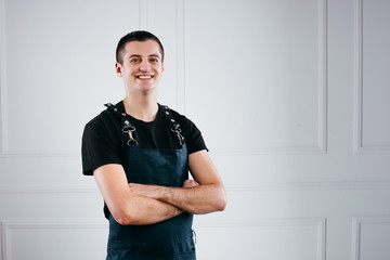 Closeup of friendly smiling barista in green apron with crossed arms