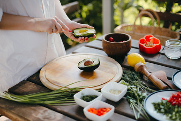 Woman's hands peeling avocado for guacamole with a spoon. Picnic cooking outside © ChesterAlive91