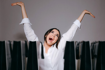 Girl is extremely happy from her Black Friday shopping. Lots of bags on the table. Isolated on grey