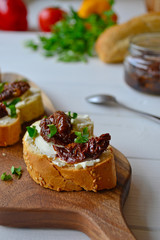 French baguette with cream cheese and dried tomatoes on a white background.