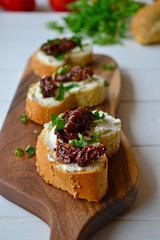 French baguette with cream cheese and dried tomatoes on a white background.