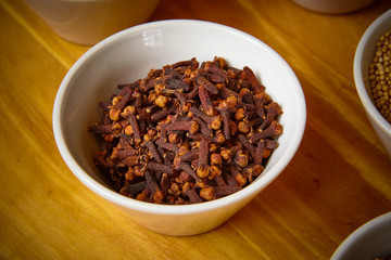 cloves in white bowl on wooden background