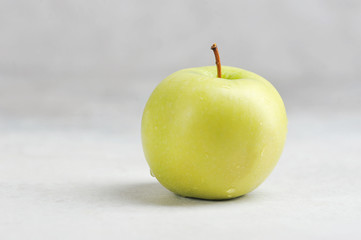 one green Apple on a gray background