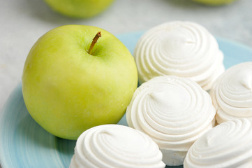 white marshmallows on a blue plate and green apples