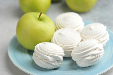 white marshmallows on a blue plate and green apples