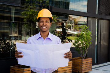 Professional architect holding blueprints outdoors.