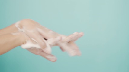 Close up of Asian women Cleaning hands with white soap bubbles on blue background. Hand washing demonstration for virus protection. Concepts of hygiene and prevention of covid 19