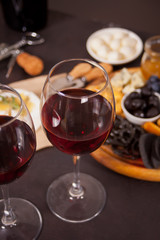 Two glasses of red wine and plate with assorted cheese, fruit and other snacks for party