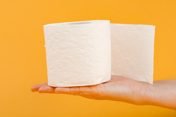A roll of toilet paper in a woman's hand on a yellow background