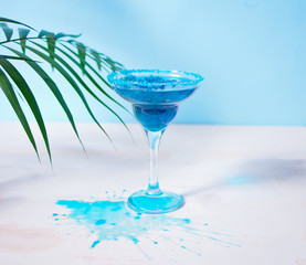 Glass of blue cocktail under a palm leaf. Hawaiian cocktai, lagoon cocktail, curacao.