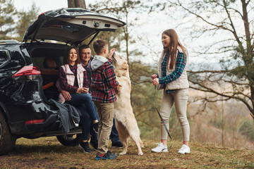 Fototapeta premium Happy family have fun with their dog near modern car outdoors in forest