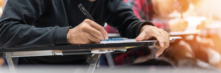Exam at school with student's taking educational admission test in class, thinking hard, writing answer in university classroom, education and world literacy day concept