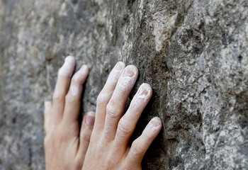 close up of a climbers chalk-covered hands on a rock wall