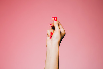 Woman's snapping hand with bright manicure isolated on pink background