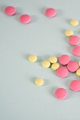 Multicolored round medical tablets on a gray background. Space for text