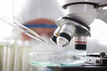 Scientist dosing a drop with pipet to exam with microscope