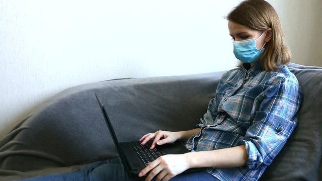 Woman in medical mask is working from home. Online freelance during the time of quarantine. Laptop in hands. Coronavirus pandemia. Economics crisis alternatives.