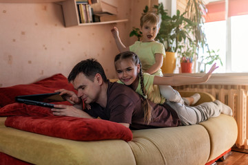 Happy man with children using laptop and earphone during his home working, life in quarantine