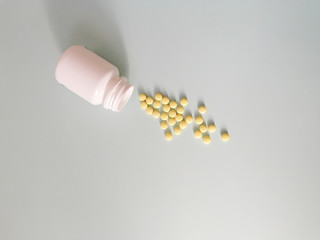 Yellow pharmaceutical medical tablets, tablets and a white vial on a blue background. Copy space.
