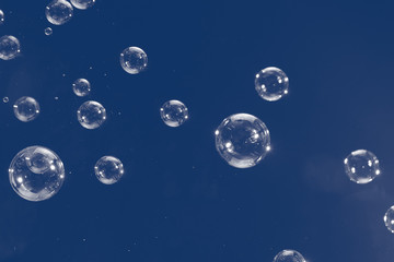 Flying soap bubbles isolated on blue background. Abstract background.
