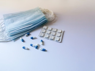 Blue medical disposable mask. Blue and white capsules. White square tablets on a white background