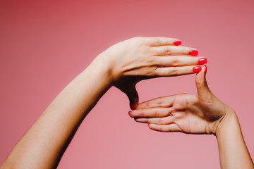 Woman's hands with bright manicure isolated on pink background frame gesture
