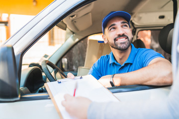Delivery man in van while customer sign in clipboard.