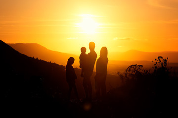 Family's silhouette at sunset with father, mother, son and daughter