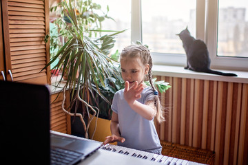 Young musician playing classic digital piano at home during online class at home, self-isolation
