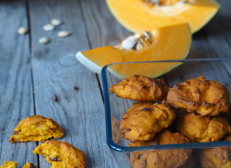 Pumpkin vegetarian cookies with raisins and cinnamon on a wooden background with a pumpkin in the background.