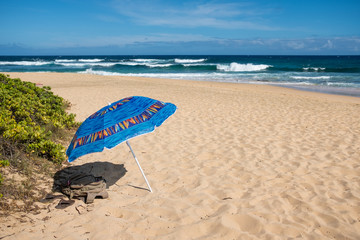 Fototapeta na wymiar Umbrella with sandals on an empty beach, going for a swim