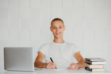Young smiling student sitting at laptop and studying. Isolated on white.